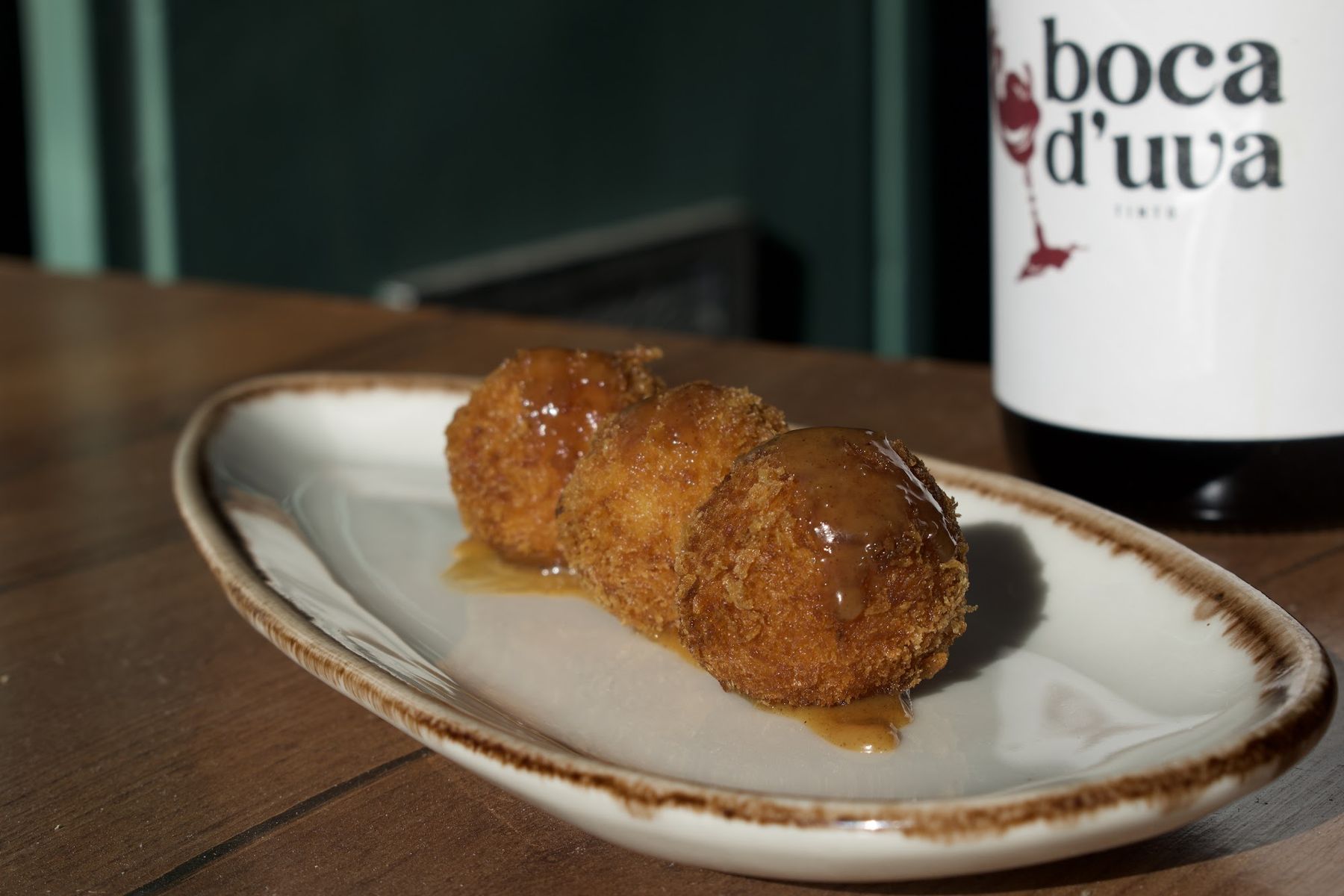 Croquete dourado com garrafa da casa ao lado