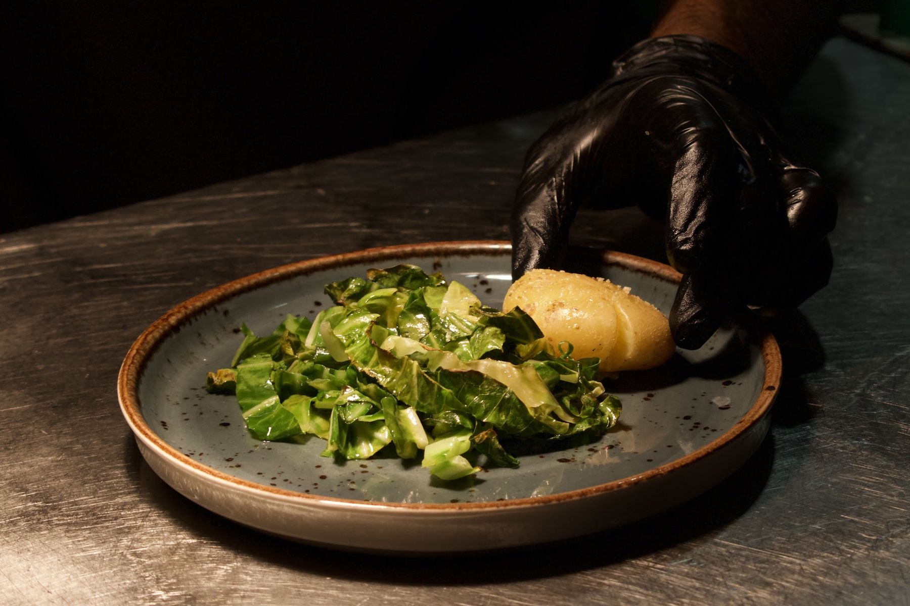 Prato de legumes e batata empratado com luvas de serviço
