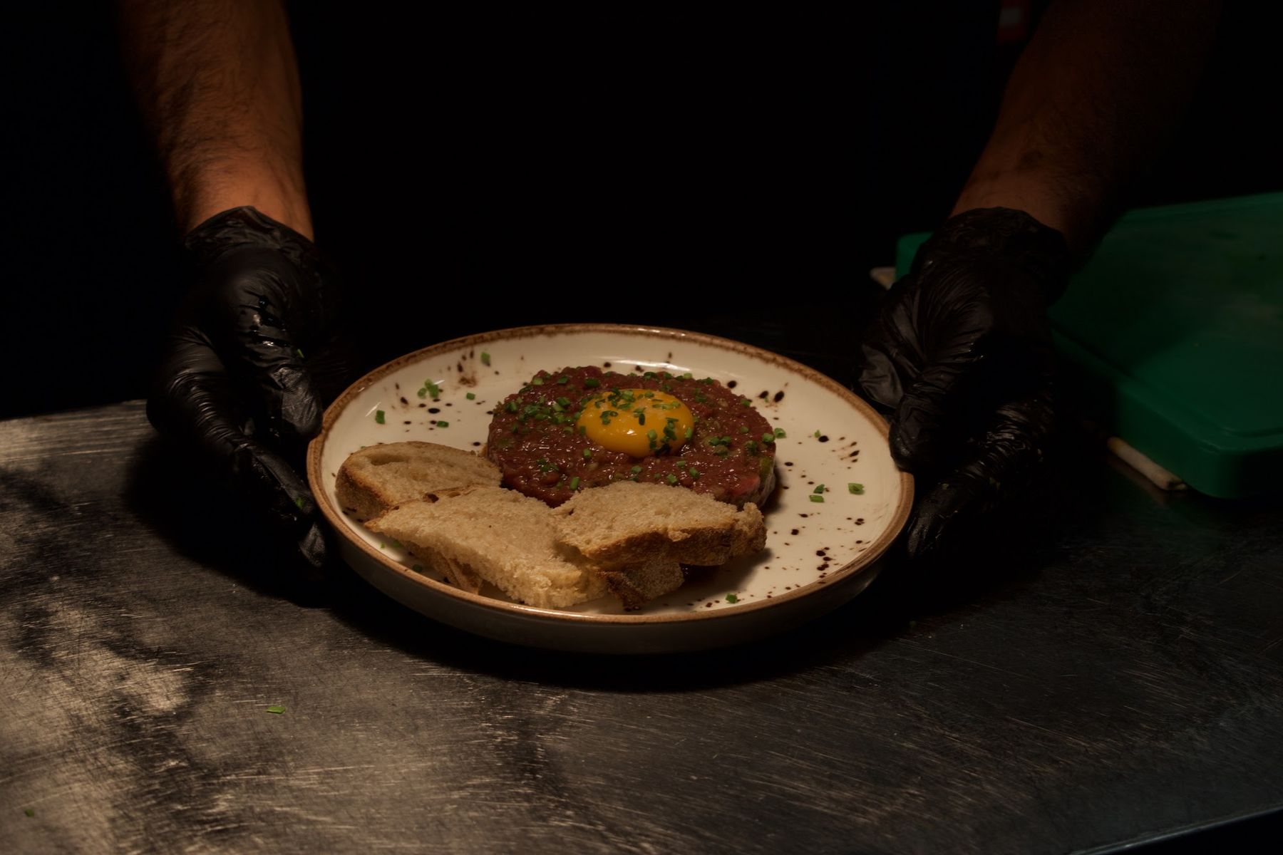 Prato de carne com ovo, servido com as mãos à mesa