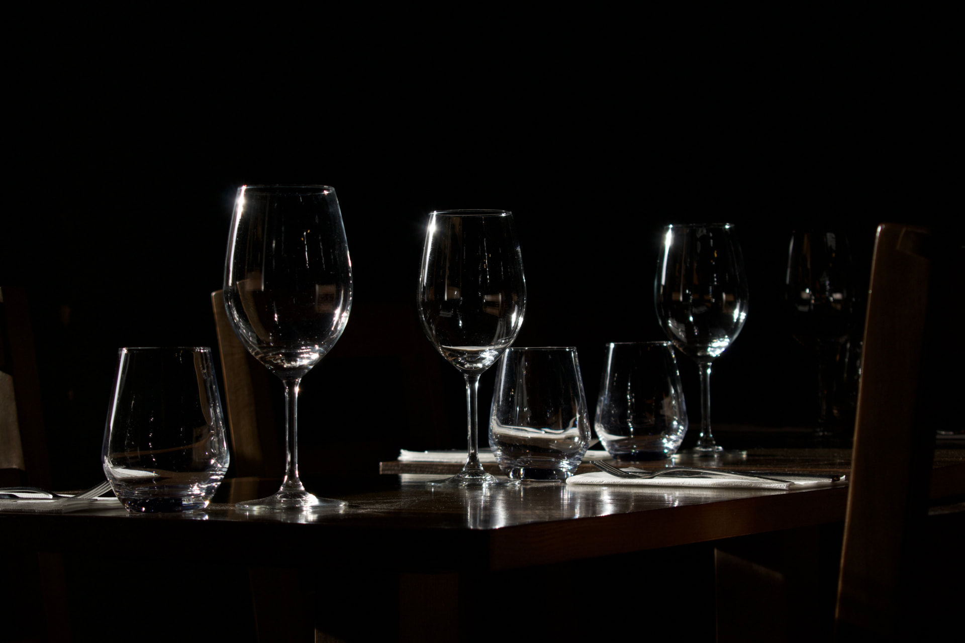 Copos de vinho e mesa posta à luz baixa no Boca d'Uva